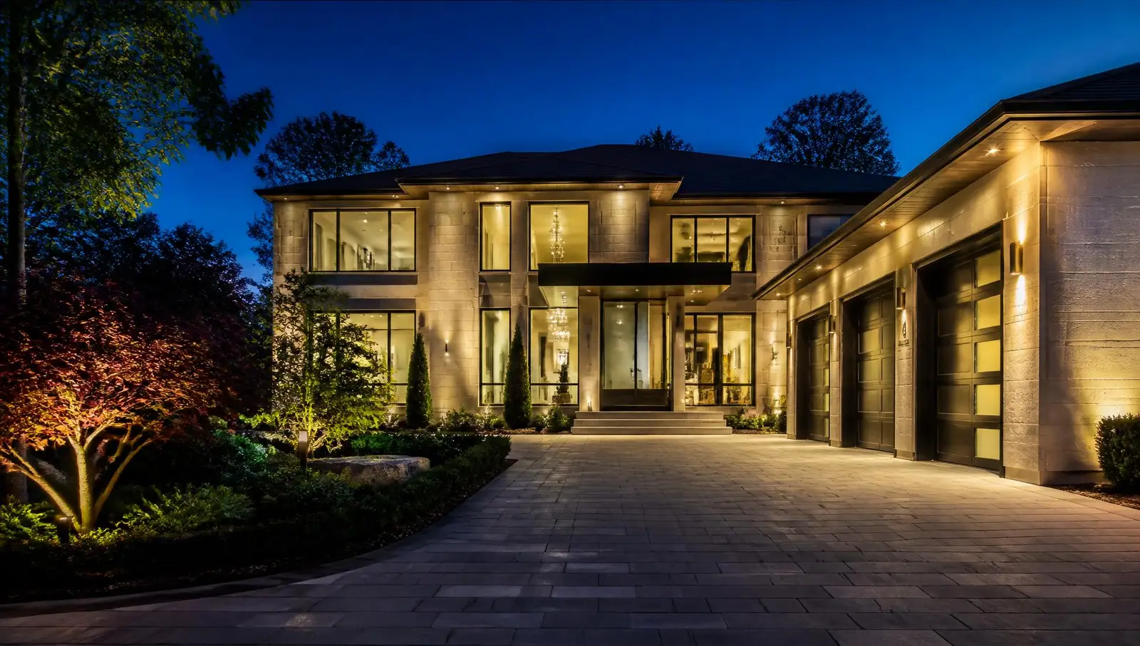 Paver driveway, roof edges and front entrance of a home at dusk